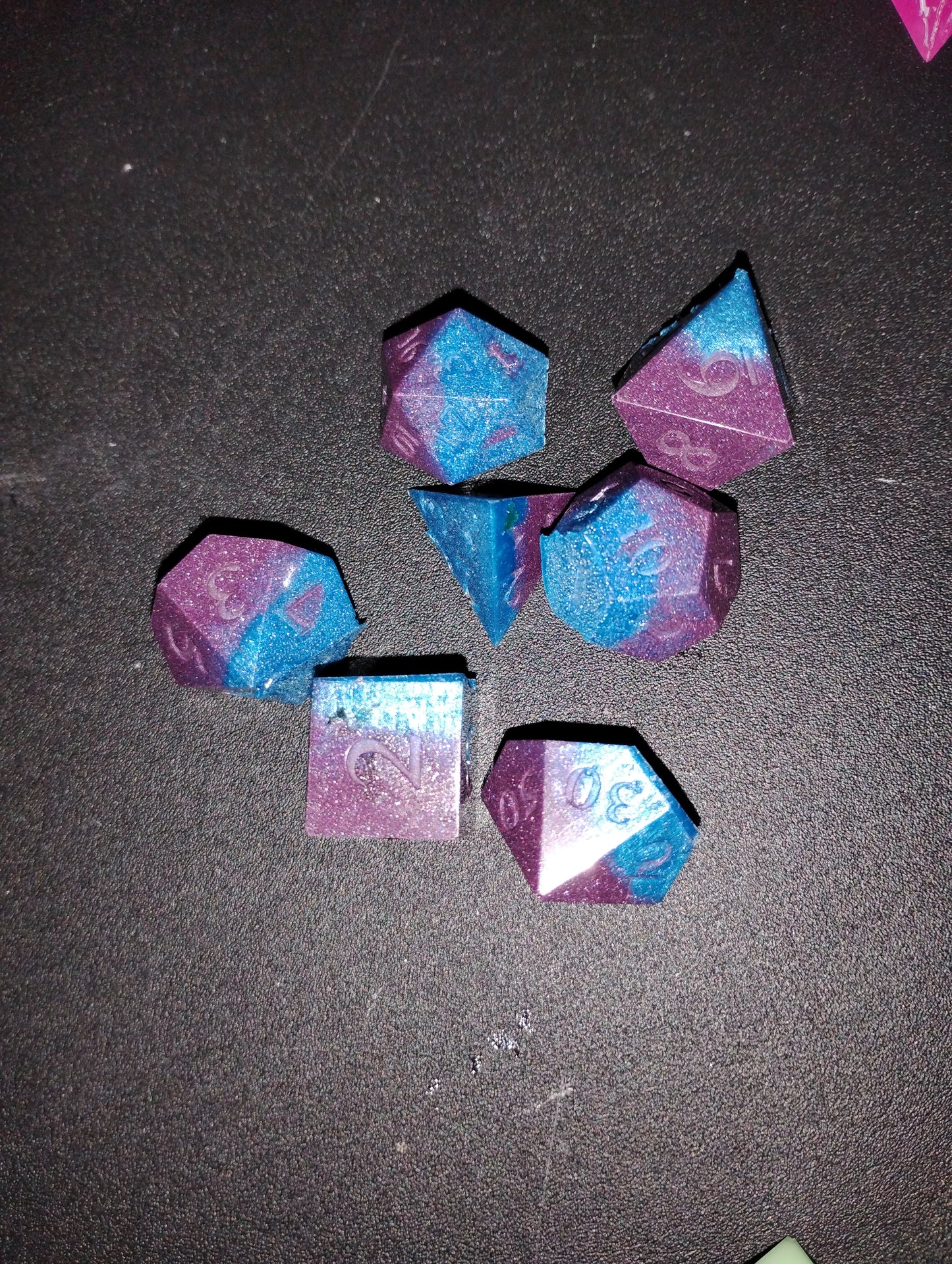 Set of purple and blue polyhedral dice on a dark surface