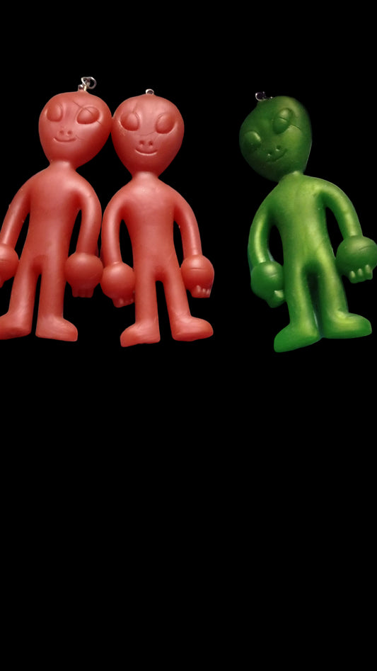 Two plastic toys, one green and one red, on a white fabric background.