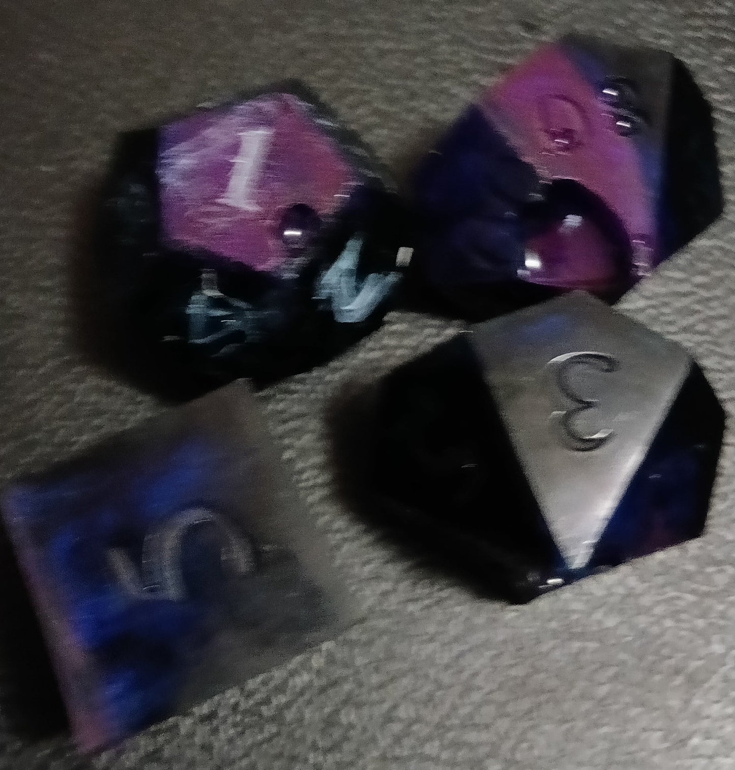 Polyhedral dice with purple and black faces on a textured surface