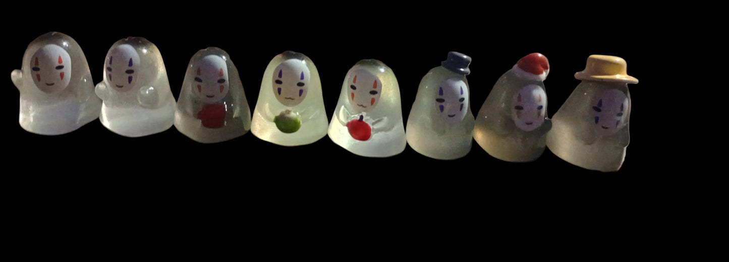 Row of glass figurines with various facial expressions and accessories on a black background