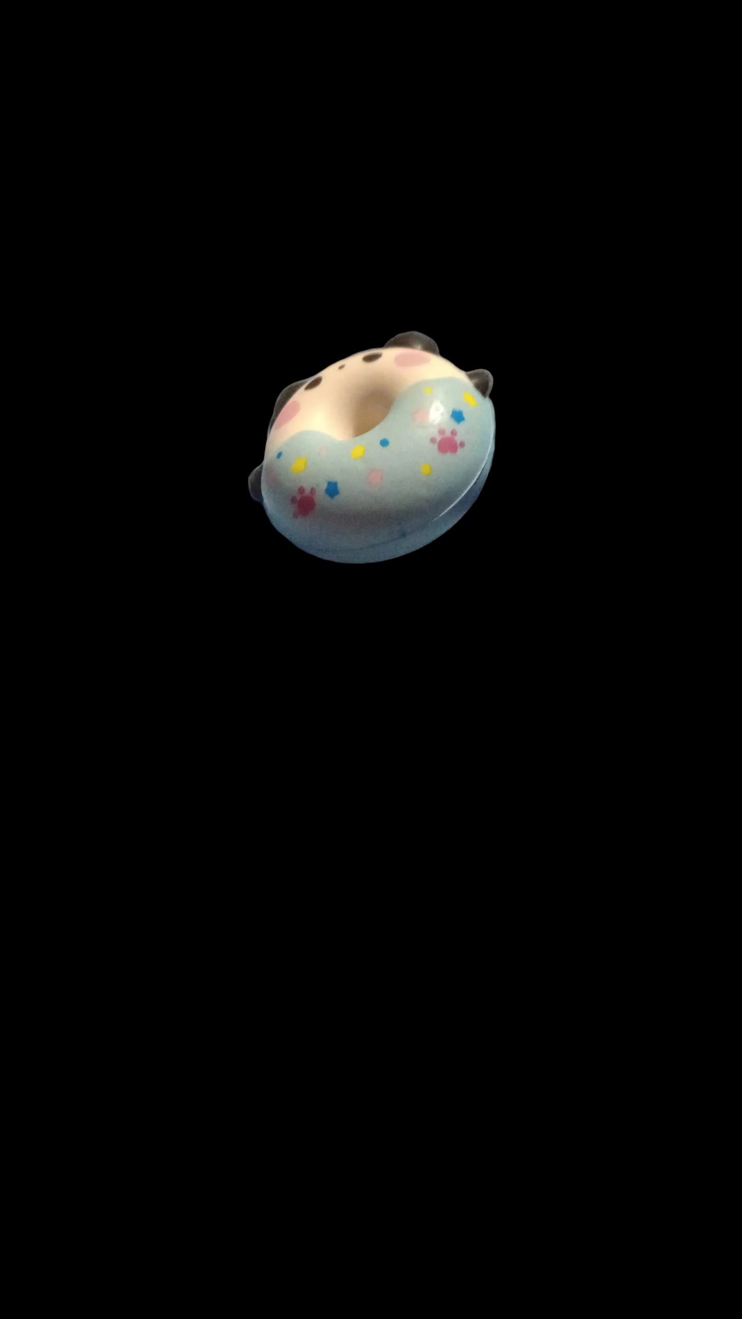 Small donut-shaped toy with a face on a textured surface